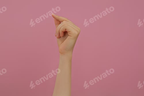 Preview: Woman showing thumb and index finger together on pink background, closeup