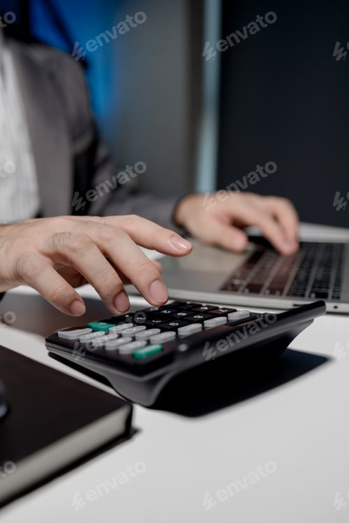 Preview: An employee is seriously calculating numbers in an important document, A calculator is used by a you