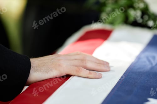 Preview: Closeup of male hand on coffin with American flag