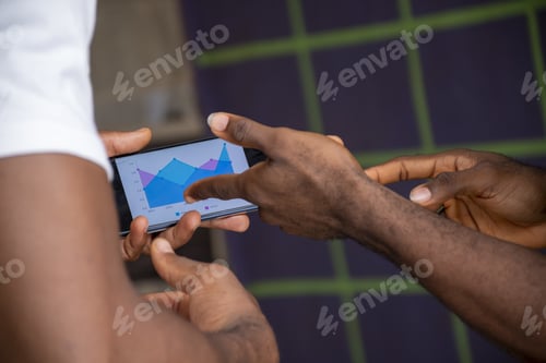 Preview: Closeup of two African people discussing a chart on a mobile device - future planning concept
