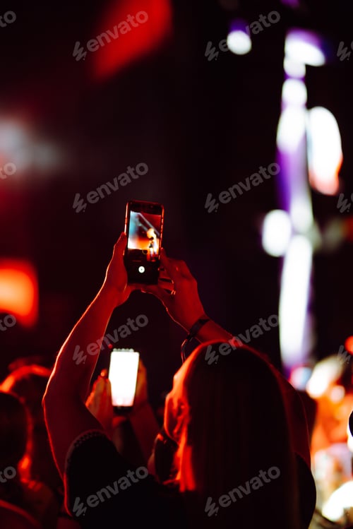 Preview: Hand with a phone records live music festival. People taking photographs with smart phone.