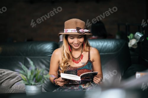 Preview: Young woman reading book and fresh cup of coffee on the table