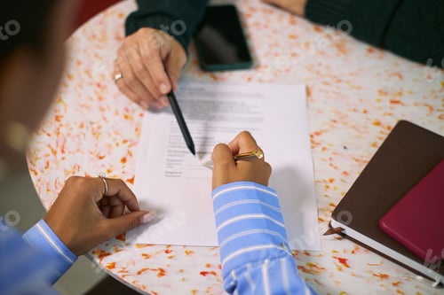 Preview: Two Young Adult Women Collaborating on Business Document at Table
