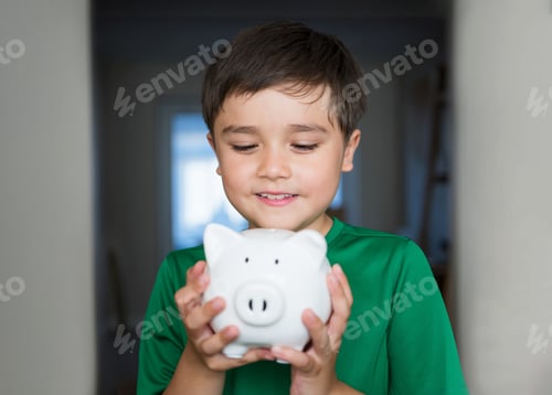 Preview: Happy boy holding piggy bank.cheerful child showing money saving box. kid Learningsaving for future