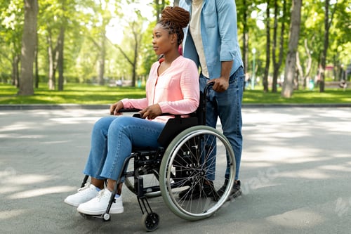 Preview: Disabled black woman in wheelchair on walk with her affectionate husband outdoors, spending great