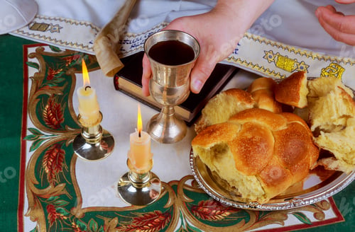 Preview: Shabbat eve table with uncovered challah bread, Sabbath candles and Kiddush wine cup.
