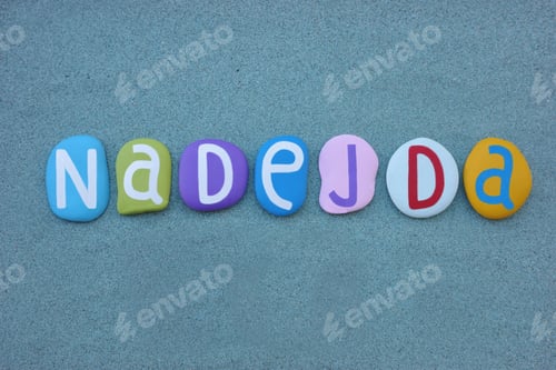 Preview: Nadejda, female given name composed with multi colored stone letters over green sand