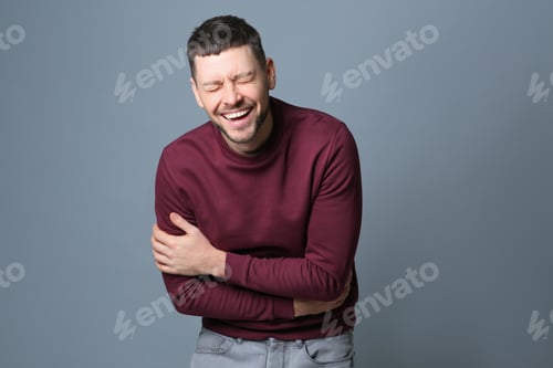 Preview: Handsome man laughing on grey background. Funny joke