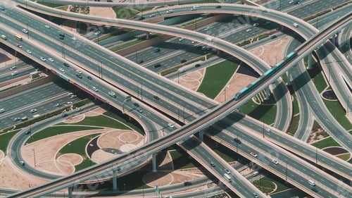 Preview: High angle shot of a big highway with multiple roads and a train riding through the central road
