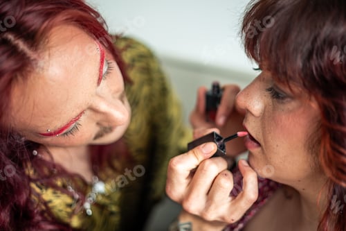 Preview: Non-binary person applying lipstick on friend celebrating body positivity