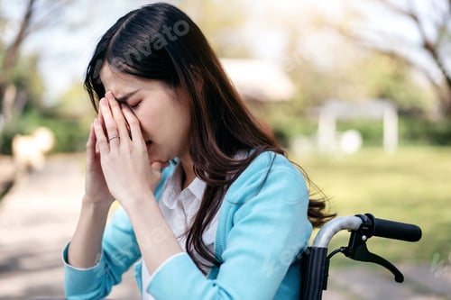 Preview: Young asian woman on wheelchair in the garden and touching hands to rubbing nose feeling stressed