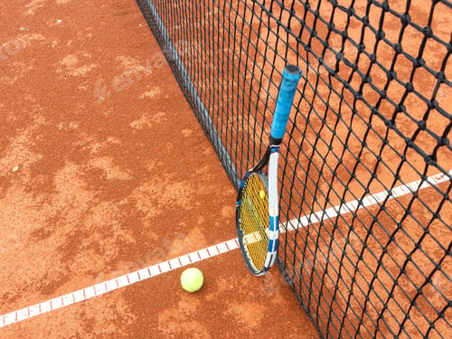 Preview: Tennis ball and racket on a clay court close-up