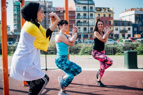 Preview: Calisthenics class at outdoor gym, young women balancing on one leg, side view