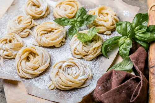 Preview: Pasta alluovo, Tagliatelle or fettuccine. Round balls of raw pasta on the wooden cutting board