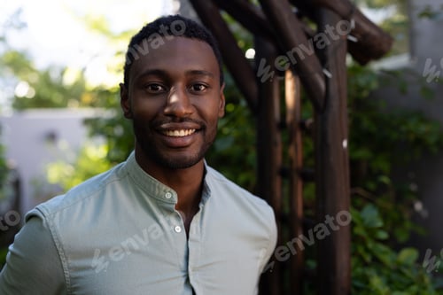 Preview: Smiling African American man standing outdoors, enjoying sunny day in garden