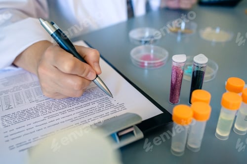 Preview: Female scientist hand filling investigation form of small plastic particles on glitter composition