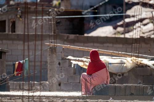 Preview: Woman in red headscarf relaxes in the mountains of Morocco during a sunny day