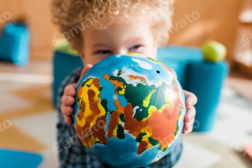 Preview: selective focus of smart kid covering face with globe
