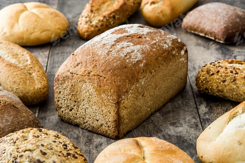 Preview: Different types of bread loaf and rolls resting on rustic wooden table