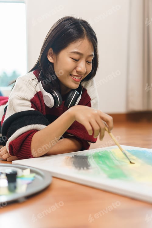 Preview: The art concept, Asian female artist lying on the floor and using paint brush to painting on canvas.