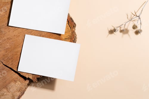 Preview: Blank white paper card on old wooden desk and beige background with flower
