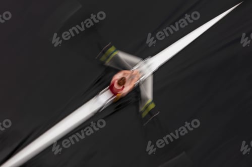 Preview: Overhead view of an oarsman in a single scull boat on calm water mid stroke, motion blur.