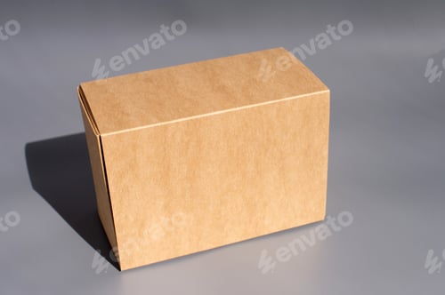 Preview: Plain cardboard box on gray background in minimalist setting. International Box Day