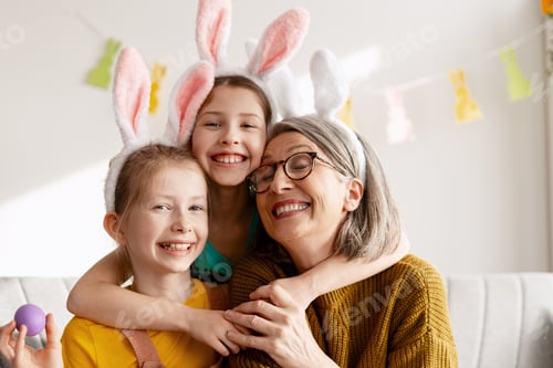 Preview: Happy grandmother and granddaughters celebrating Easter holiday, wearing bunny ears