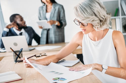 Preview: attractive young caucasian businesswoman looking at documents in office