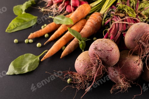 Preview: Close-up of carrots and beetroots with green peas and leaf vegetable on black background