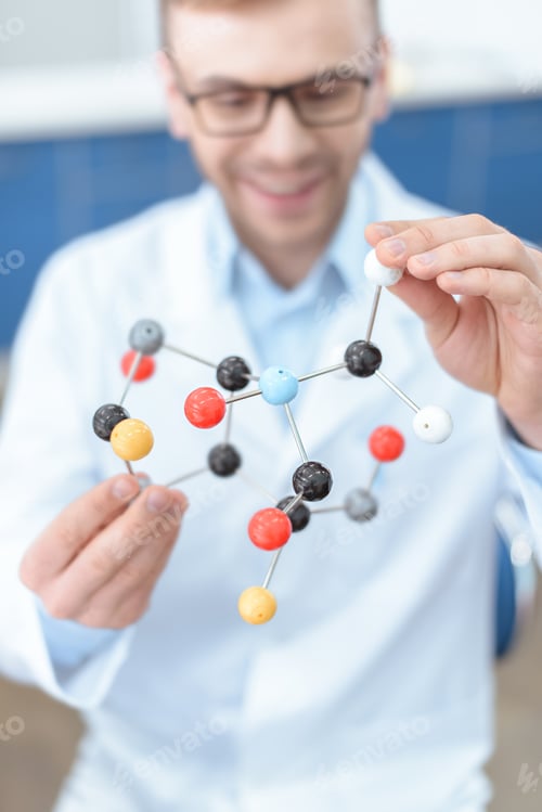 Preview: Smiling man scientist in lab coat holding molecular model