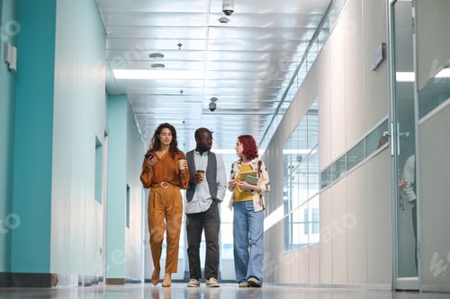 Preview: Group of young multicultural coworkers moving along corridor of building