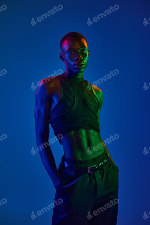Preview: Young man showcases bold fashion in vibrant lighting against a striking backdrop