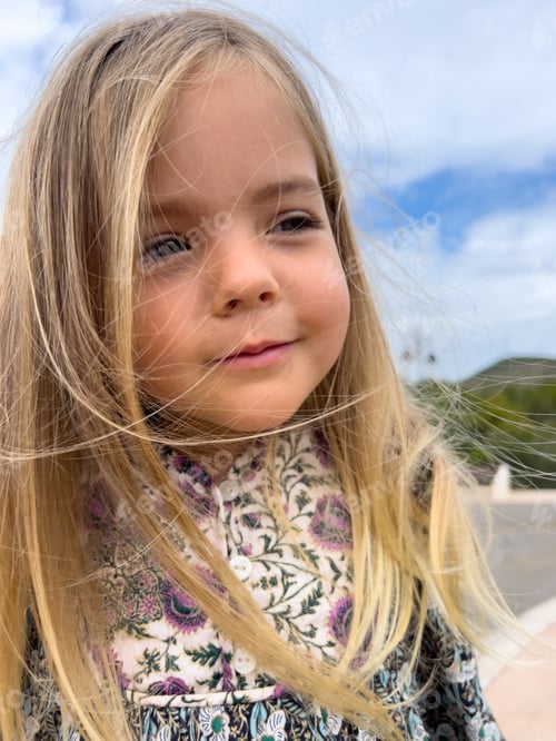 Preview: Portrait of a little girl with hair frolicking in the wind looking thoughtfully into the distance