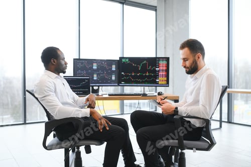 Preview: Two confident businessmen, financial analysts or investment advisers sitting at office desk