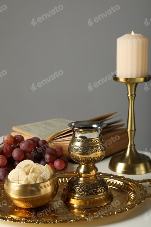 Preview: Candle, book, grapes, liturgical bread, golden cross and cup on table on gray background