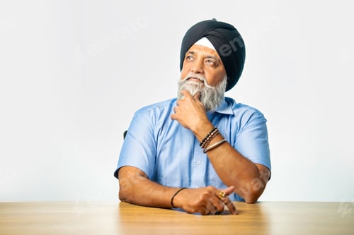 Preview: Senior Sikh man sitting at table with white background, expressing various emotions and gestures