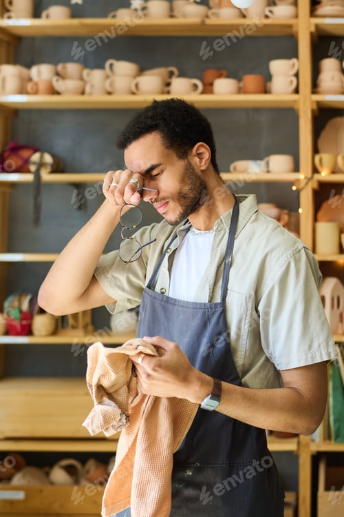 Preview: Young tired black man with towel touching his head after hard work