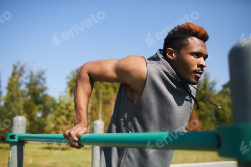 Preview: Motivated black man doing dips outdoors