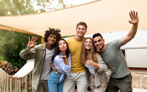 Preview: Portrait of happy young multiracial friends posing near their camper van, smiling and having fun