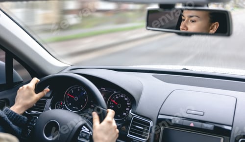 Preview: Woman drive a car reflects in back view mirror.