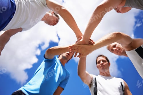 Preview: Shot of a group of young sportsmen piling their hands while standing in a huddle