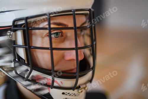 Preview: Close-up of woman floorball goalkeeper in helmet concetrating on game in gym.