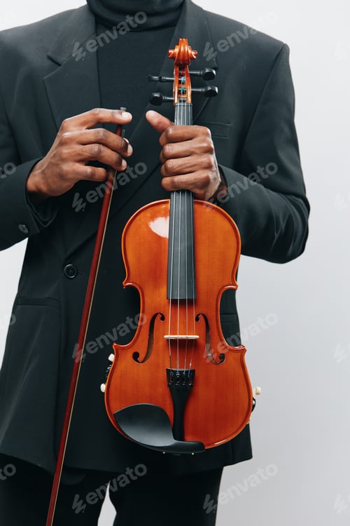 Preview: Elegant African American man in black suit holding a violin on a white background