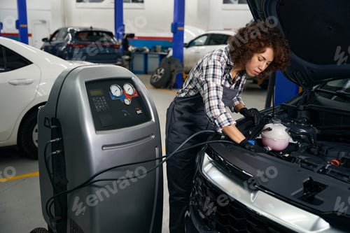 Preview: Woman auto mechanic checks a car air conditioner