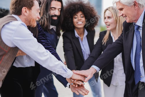 Preview: Multiracial business people stacking hands outside of office building