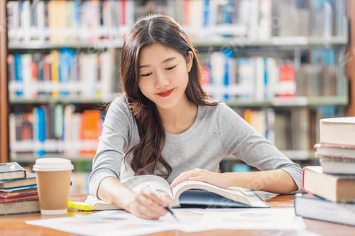 Preview: Asian young Student in casual suit reading and doing homework in library of university
