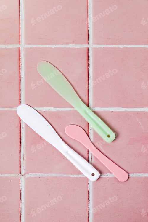 Preview: Spatulas for applying face mask or cream on pink tiled background.