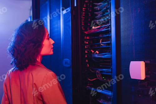 Preview: engineer checking server while working in data center in neon light