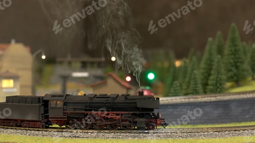 Preview: A model train running along tracks outdoors in forest.